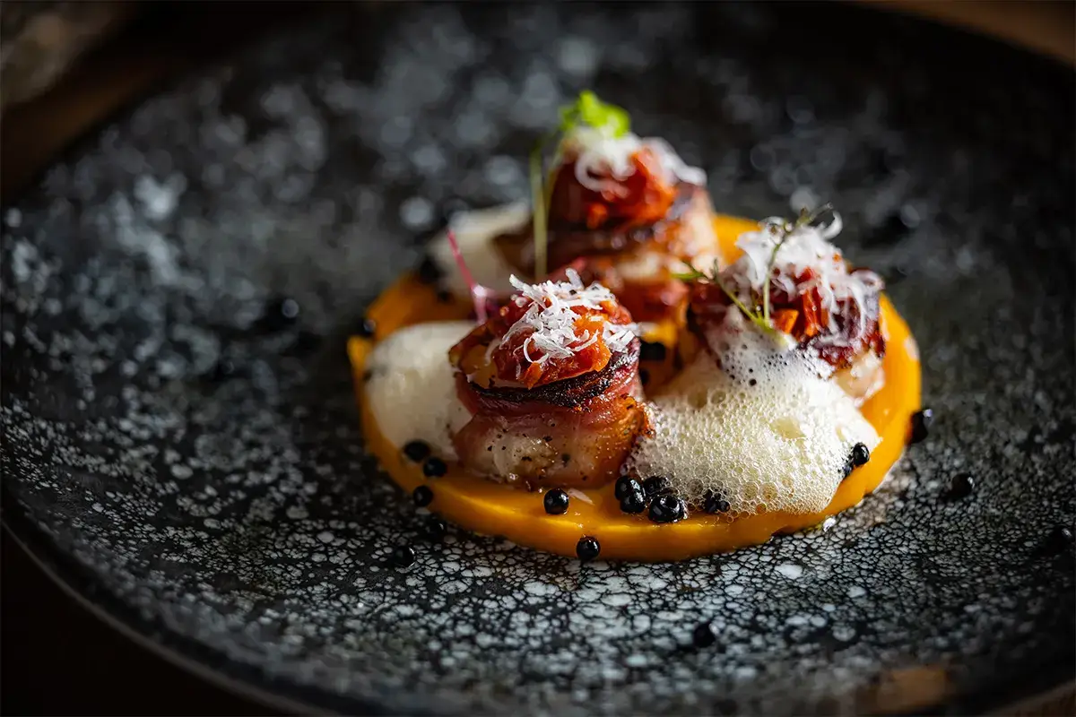 Capesante al guanciale croccante con purea di zucca, finferli e gocce di aceto balsamico Capesante al guanciale croccante con purea di zucca, finferli e gocce di aceto balsamico