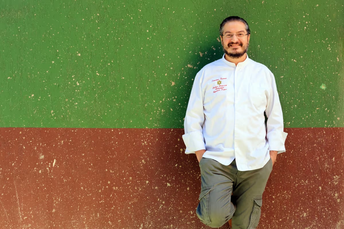 Chef Damiano Ferraro in cucina a Montallegro, con vista sul mare, mentre prepara un piatto tipico siciliano