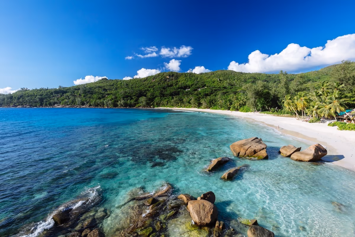 Spiaggia tropicale con mare turchese, rocce granitiche e vegetazione rigogliosa alle Seychelles