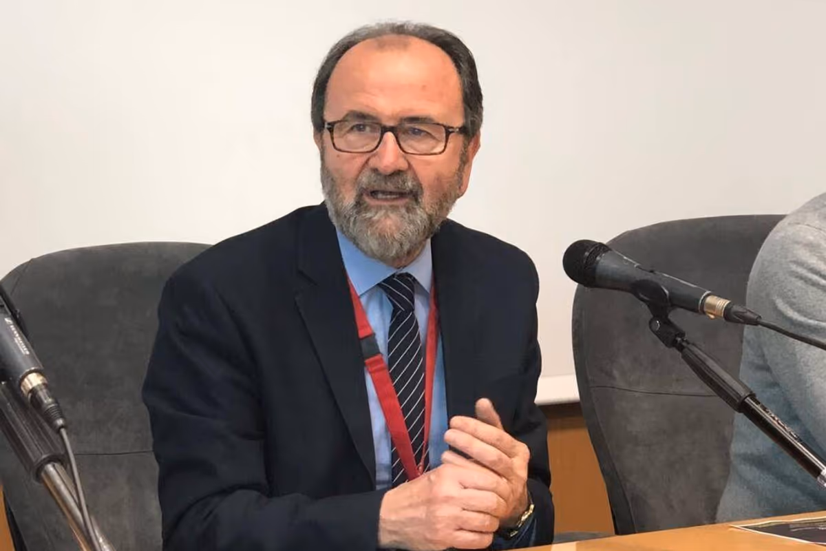 Un uomo con giacca e cravatta parla a un microfono durante una conferenza