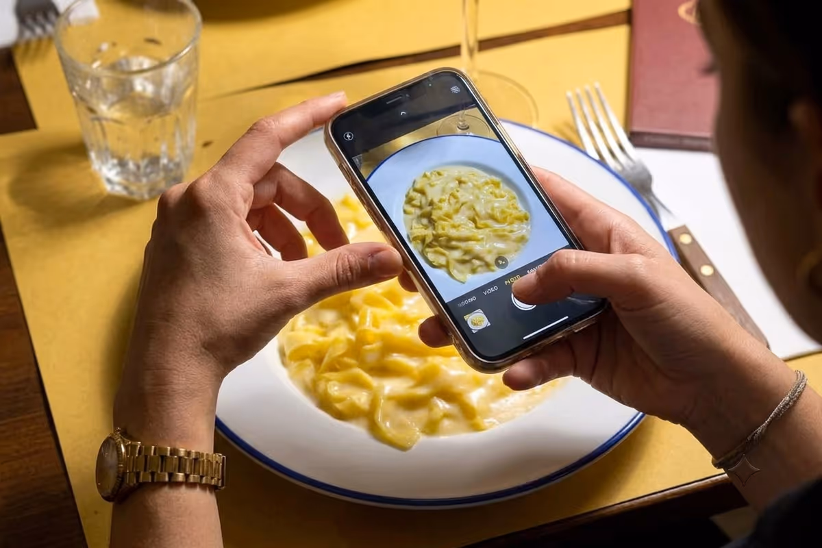 una persona inquadra con lo smartphone un piatto di tagliatelle al ristorante