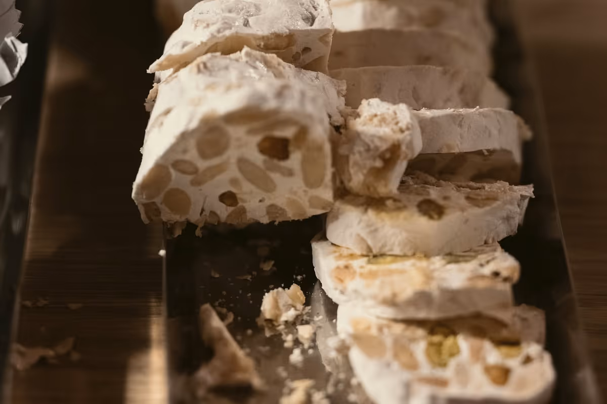 fette di torrone bianco morbido con mandorle e pistacchi su vassoio
