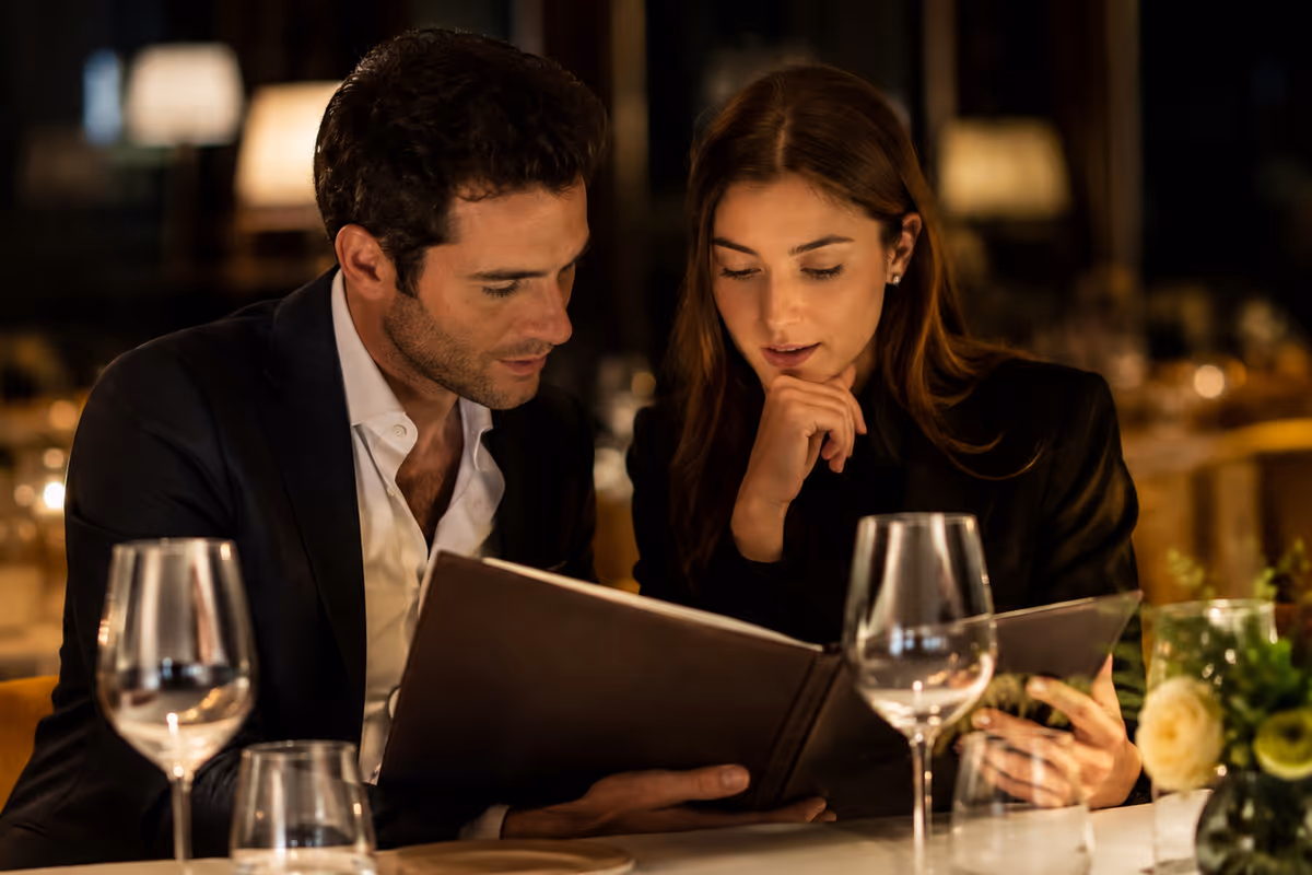 coppia in abito elegante sceglie il vino consultando il menu in un ristorante