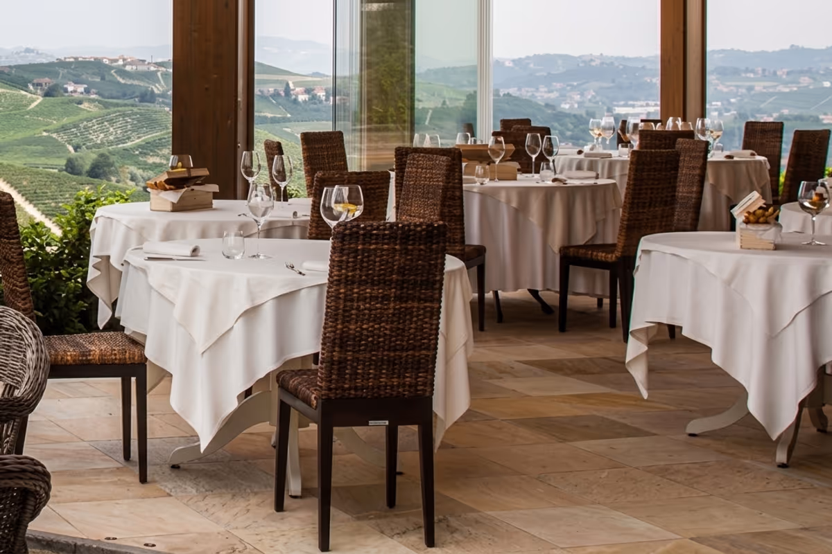 La sala interna della Locanda si apre, attraverso grandi vetrate, sul panorama dei vigneti di Cannubi, uno dei cru più celebri del Barolo
