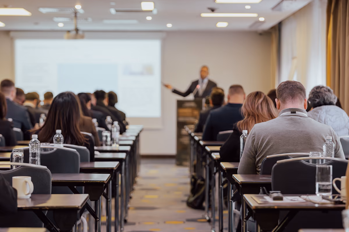 Un oratore parla durante un seminario professionale rivolto a una platea seduta in sala