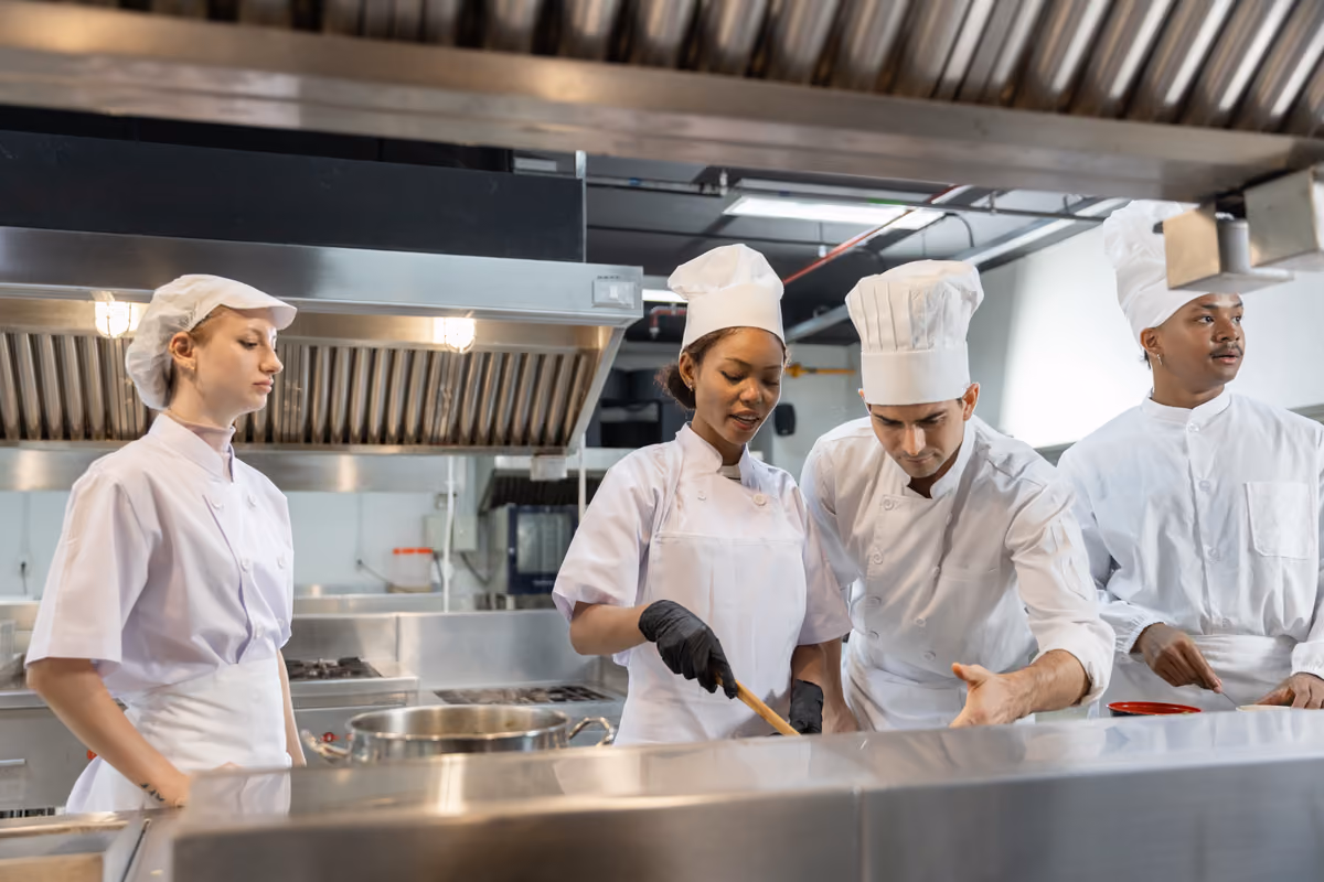 giovani cuochi in divisa lavorano insieme in una cucina professionale