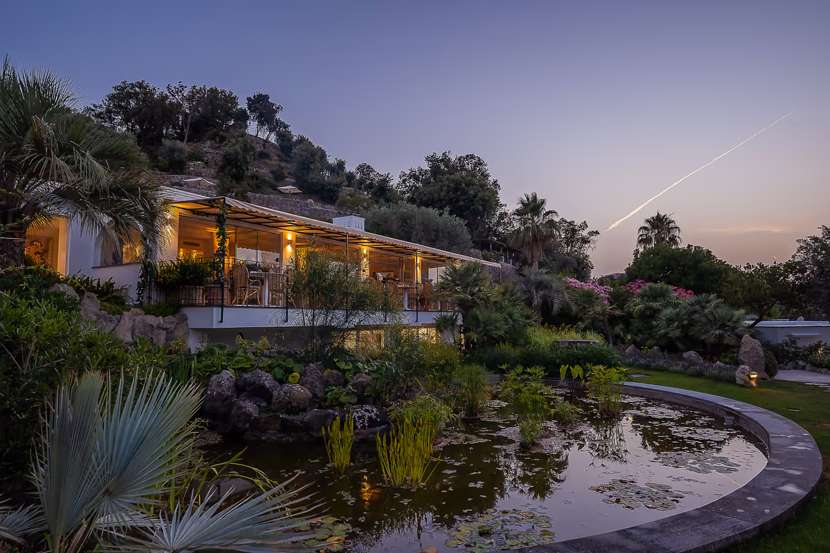 Ristorante con giardino e laghetto illuminato al tramonto a Ischia