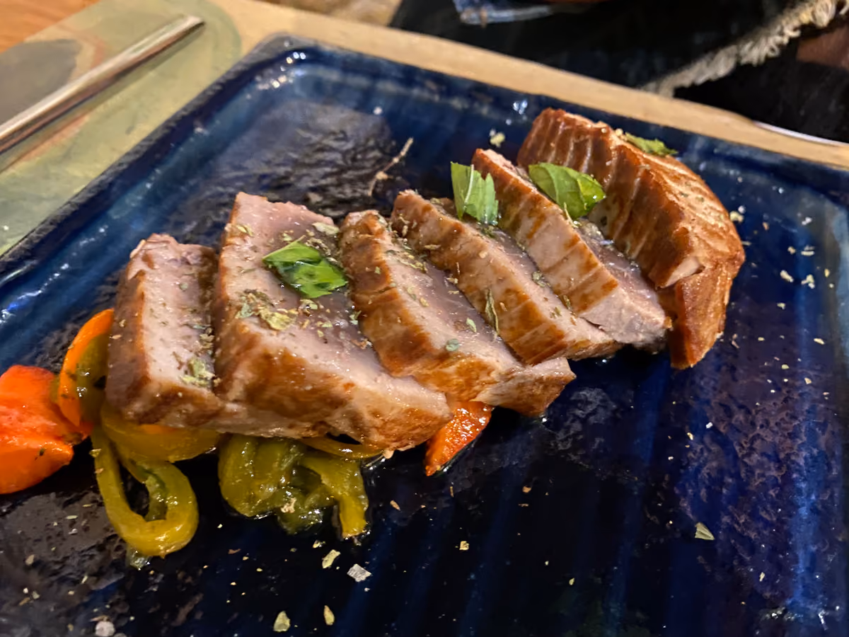 Tagliata di tonno scottato con peperoni su un piatto rettangolare blu