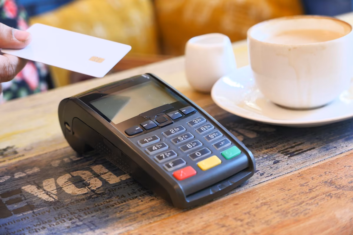 Pagamento contactless con carta di credito presso terminale POS su tavolo da caffè
