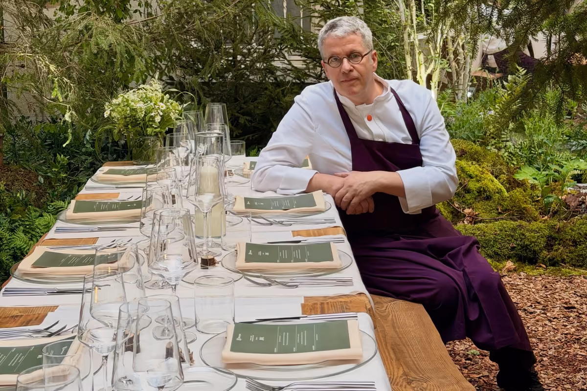 Chef Ernst Knam seduto a tavola apparecchiata in un giardino