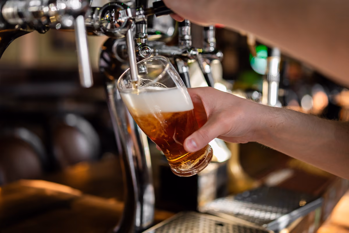 mano di un barista che spilla una birra in un bicchiere