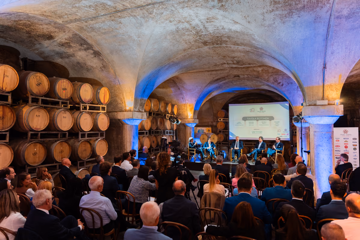 conferenza su export agroalimentare in una cantina con barrique sullo sfondo