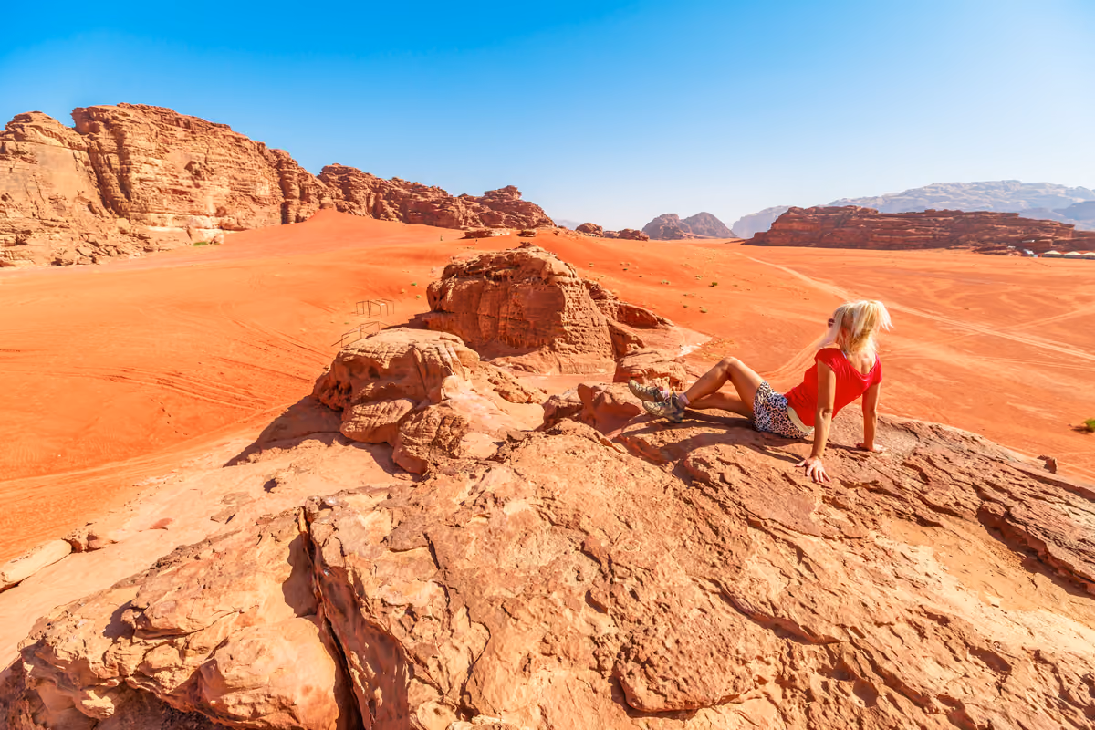 Donna seduta su una roccia nel deserto del Wadi Rum in Giordania