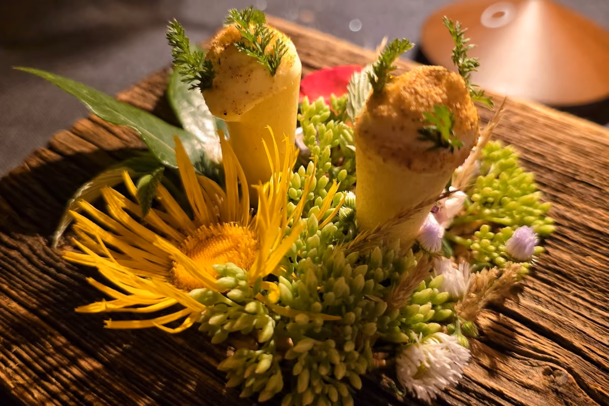 Due piccoli coni gastronomici decorati con erbe serviti su un letto di fiori