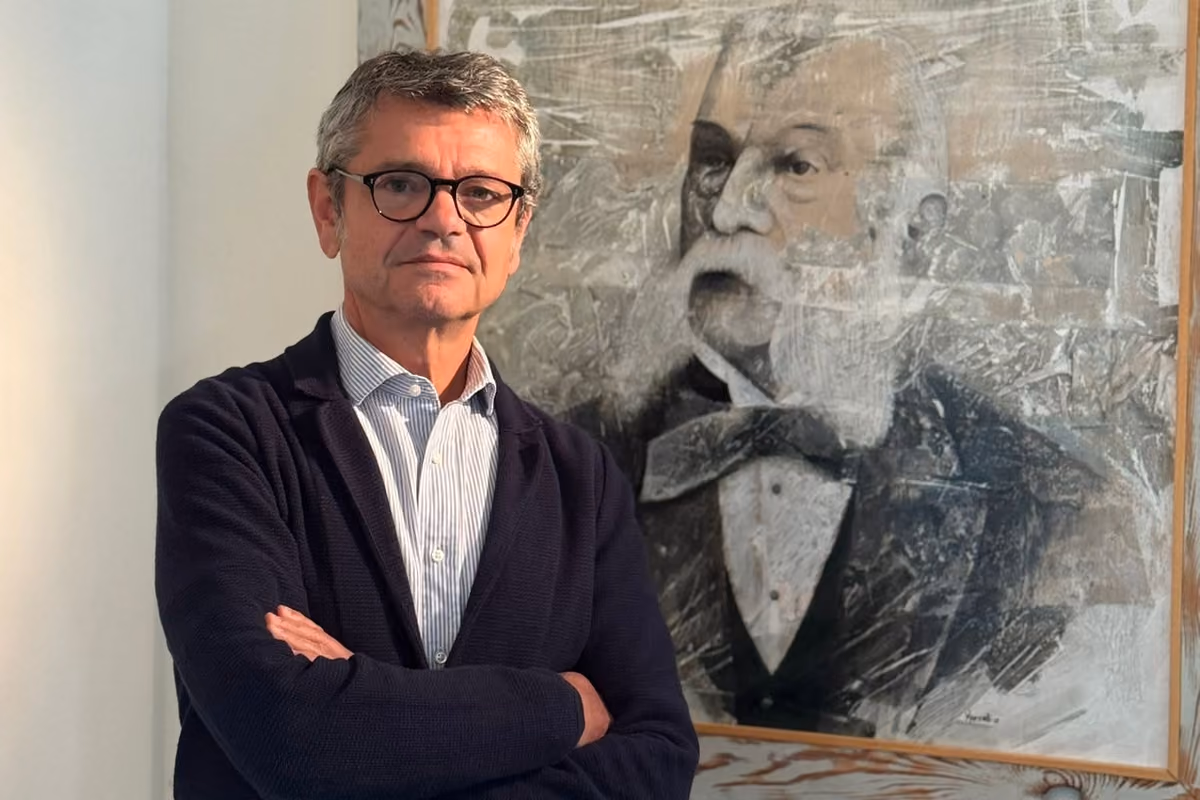 Il professor Andrea Segrè posa accanto a un ritratto dipinto