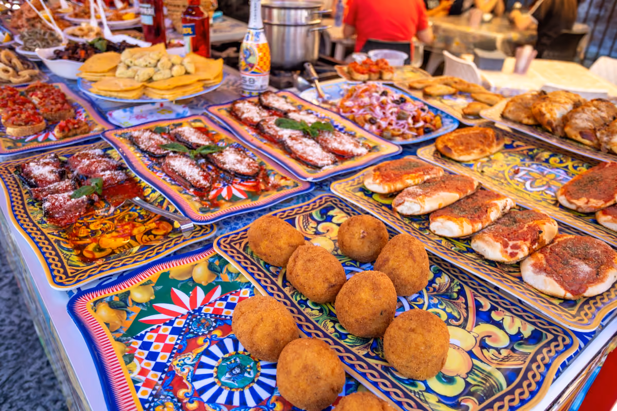 Bancarella di street food siciliano con arancini, melanzane e pizzette