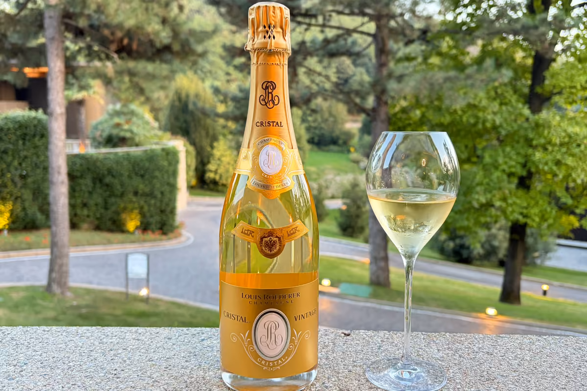 Bottiglia di Champagne Louis Roederer Cristal accanto a un calice pieno su una terrazza