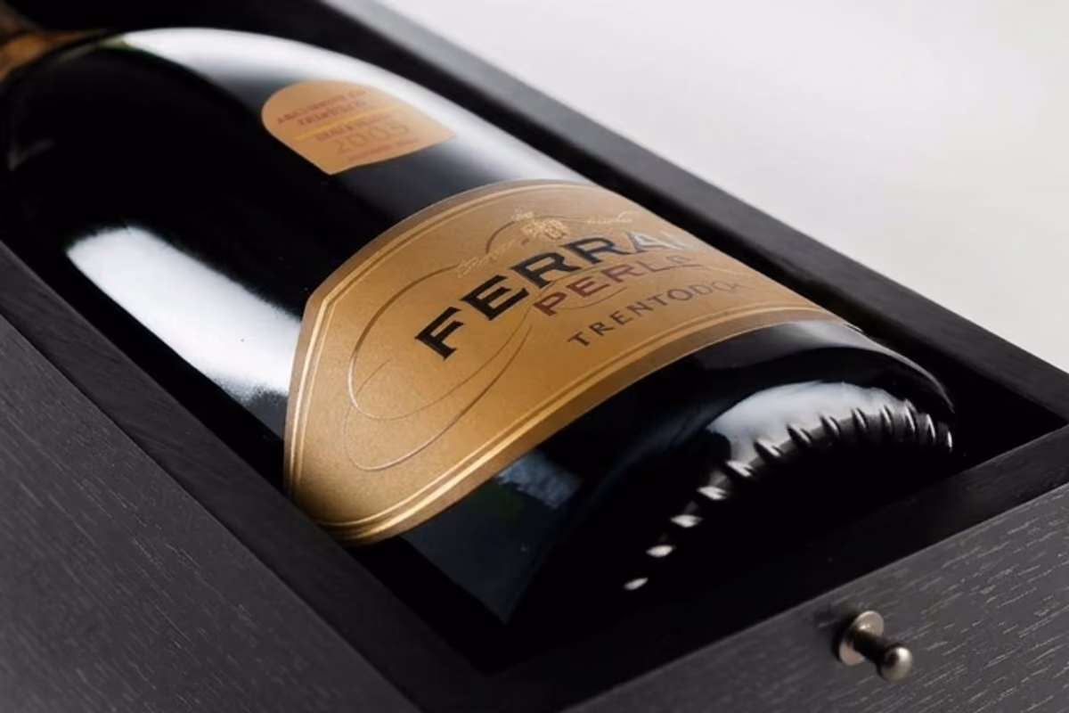 Bottiglia di Ferrari Perlé TrentoDOC riposta in un elegante cofanetto di legno scuro