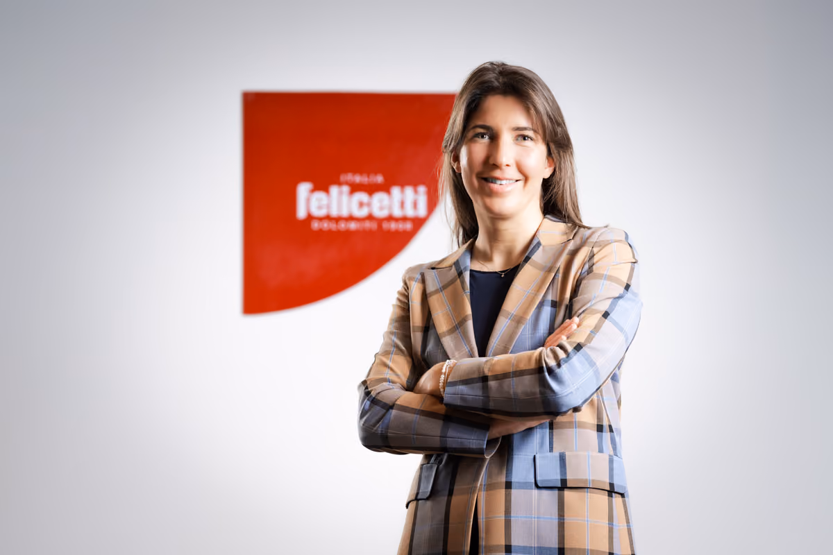 Donna sorridente indossa una giacca a quadri davanti al logo del pastificio Felicetti