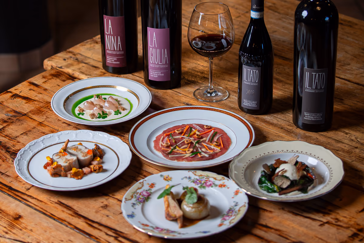 Piatti gourmet e bottiglie di vino posati su un tavolo di legno rustico