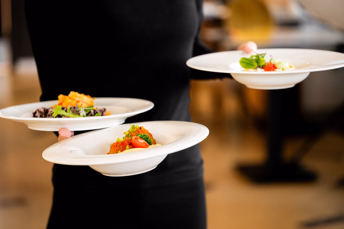 un cameriere in divisa nera serve piatti gourmet in una sala ristorante