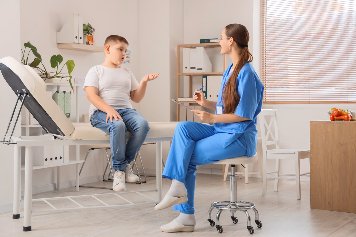 Bambino seduto su lettino medico parla con dottoressa in ambulatorio