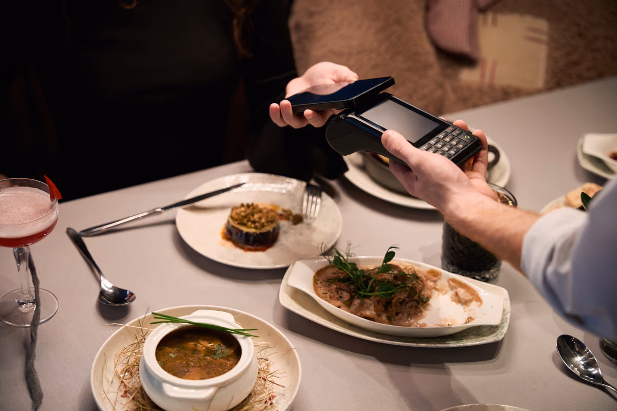 cliente paga il conto al ristorante utilizzando uno smartphone vicino a un pos