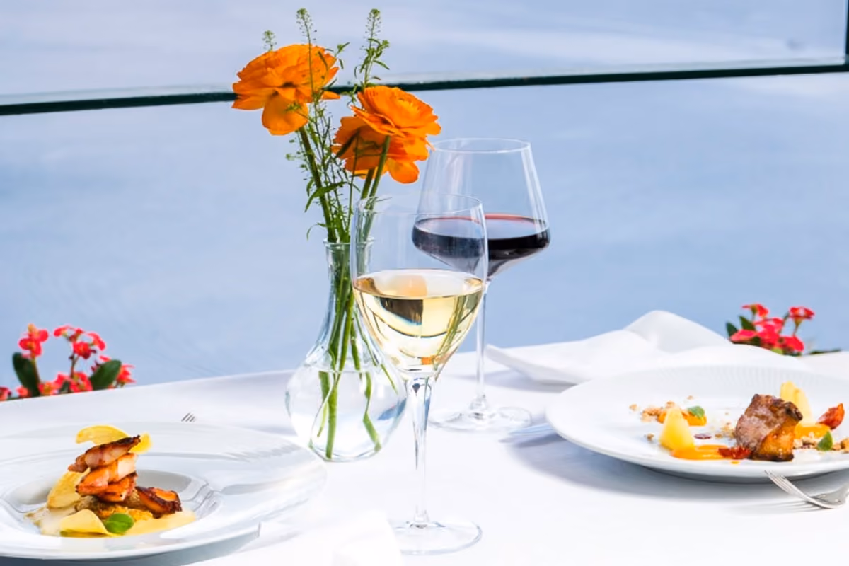 Due piatti gourmet e bicchieri di vino su tavola vista mare