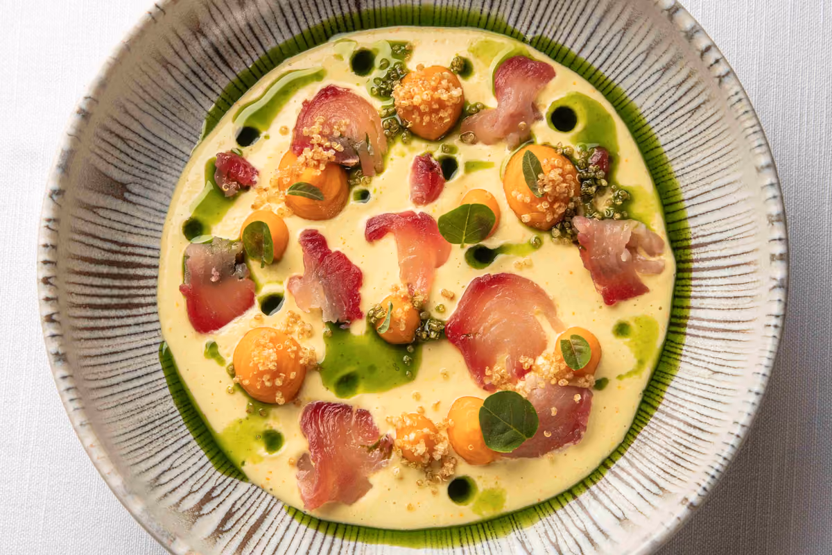 piatto gourmet con pesce crudo, crema gialla e gocce di olio verde
