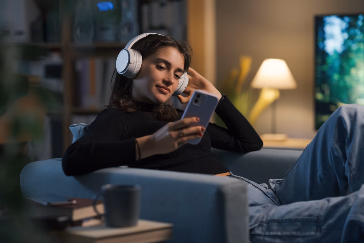 ragazza con cuffie ascolta un vodcast mentre guarda il proprio smartphone
