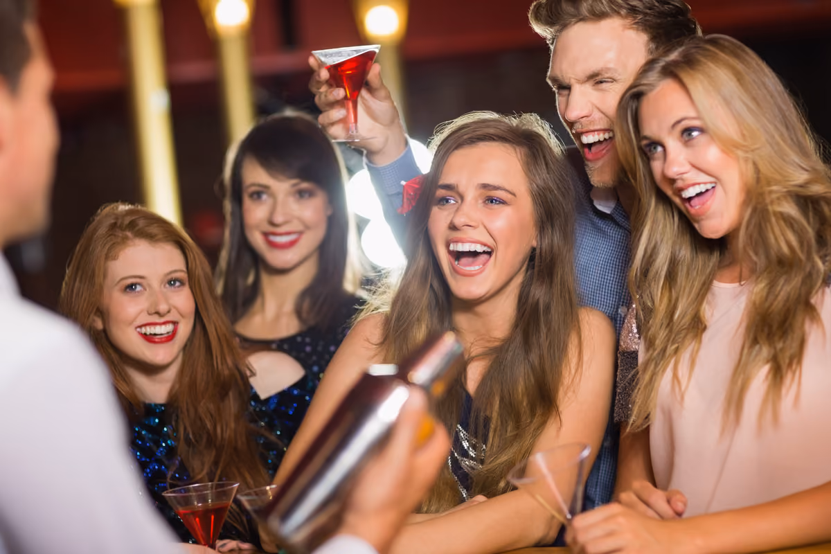 Gruppo di giovani allegri che brindano con cocktail in un locale notturno