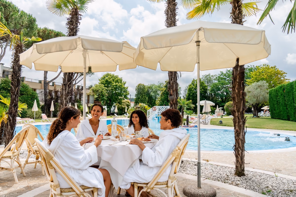 Quattro persone in accappatoio pranzano all'aperto a bordo piscina all'Hermitage di Abano Terme