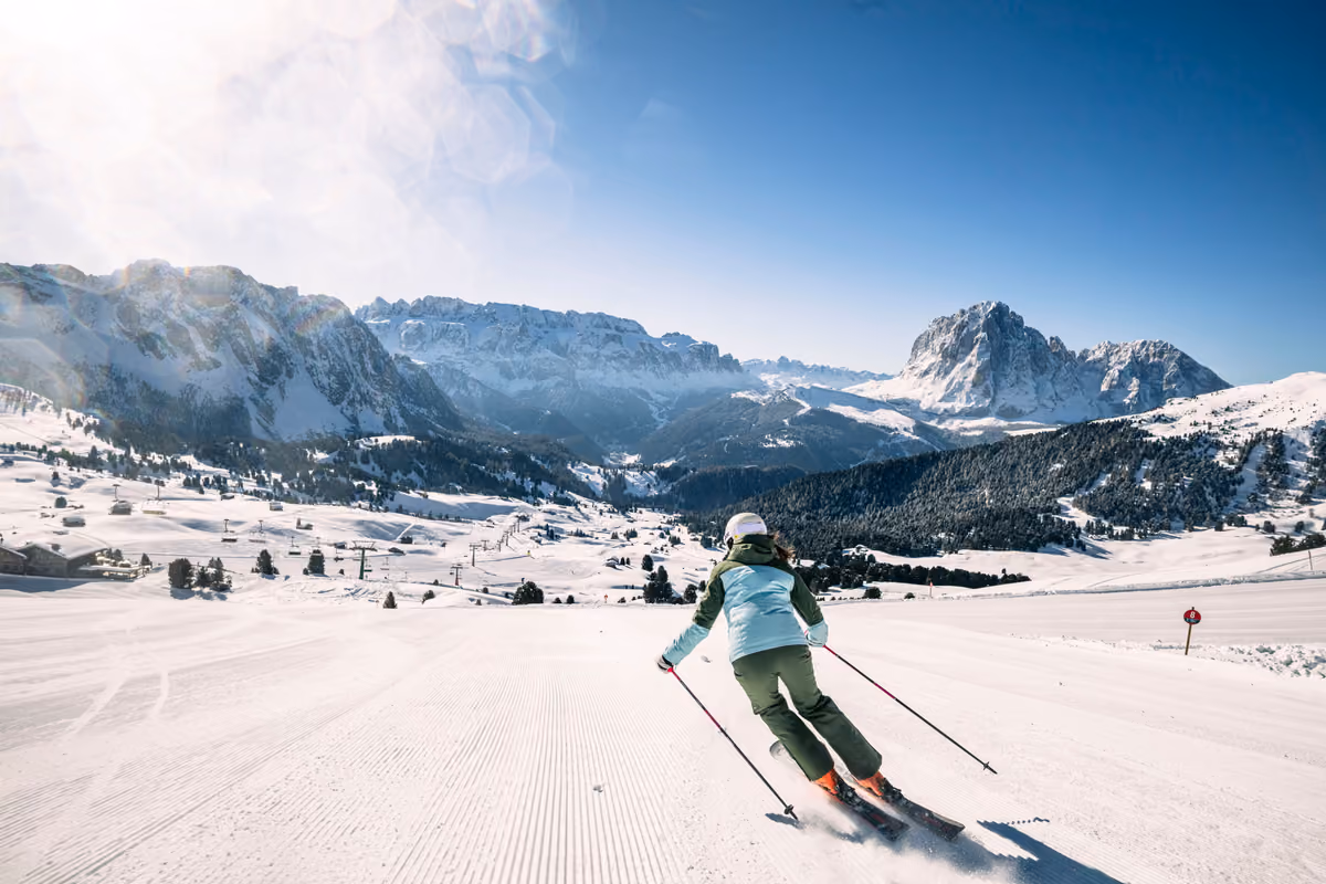 Sciatrice in discesa su una pista innevata tra le montagne della Val Gardena