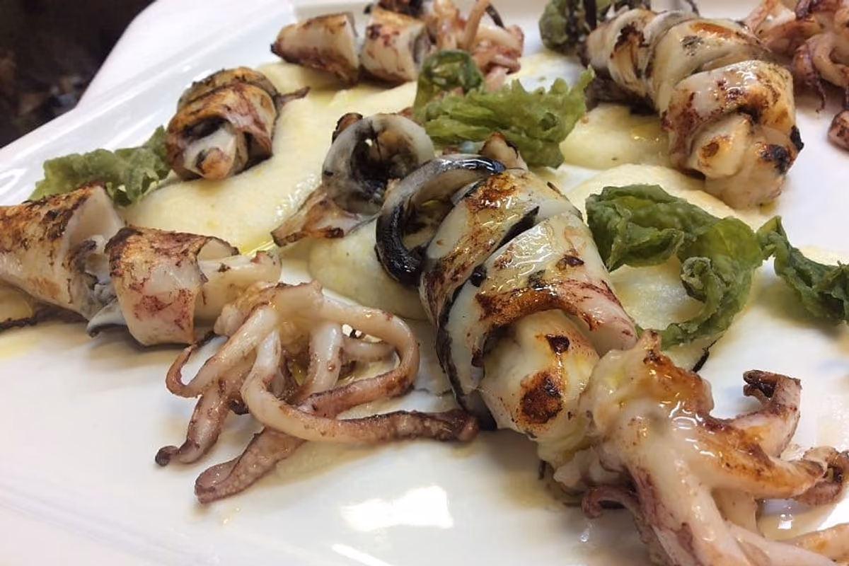 calamari grigliati su letto di purea con guarnizione verde