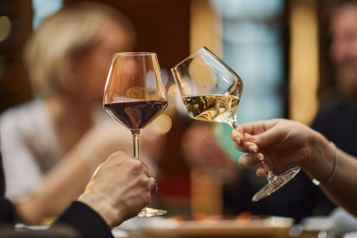 Due persone brindano con un calice di vino rosso e uno bianco