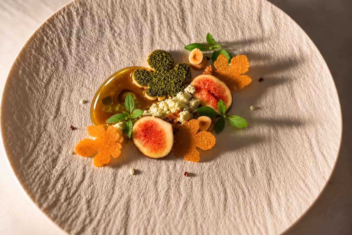 Un piatto gourmet con fichi, biscotti a forma di foglia e salsa