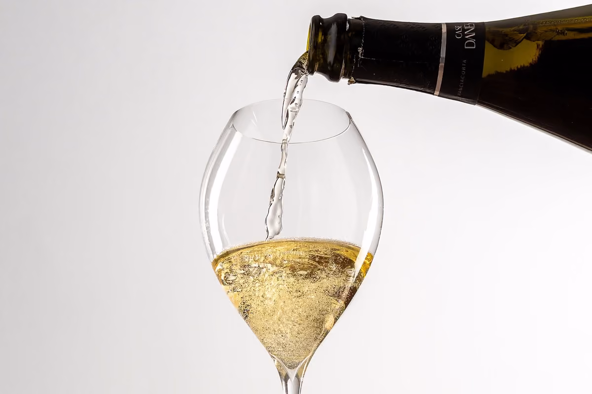 Vino spumante Case Danesi versato da una bottiglia scura in un calice