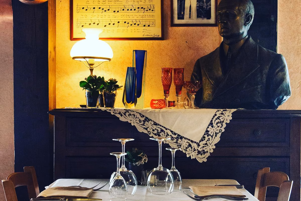 Tavolo apparecchiato in un'osteria con busto di bronzo e lampada vintage
