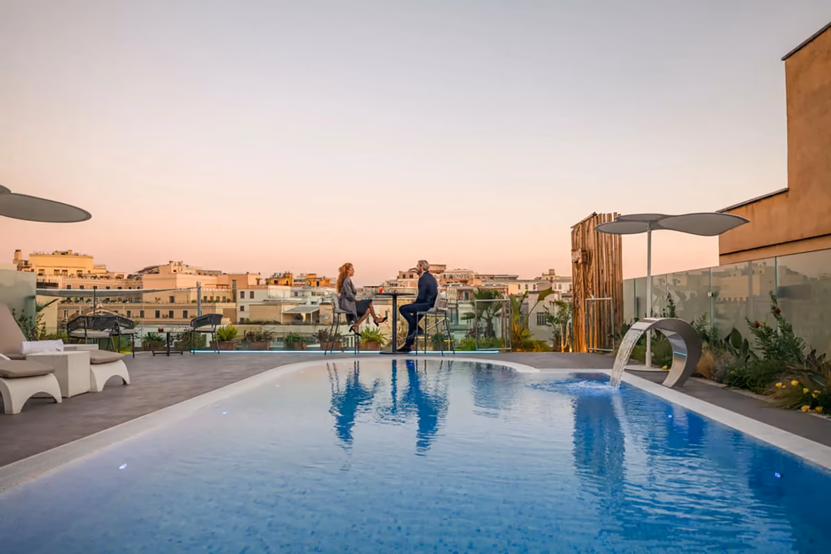 coppia seduta a un tavolo sul rooftop dell'Aleph Hotel con piscina panoramica a Roma