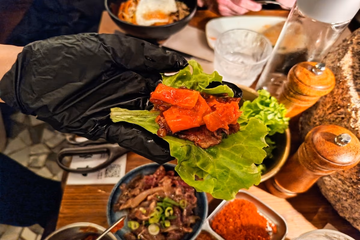 Un involtino fai da te, con un pezzo di diaframma grigliato e del Kimchi, avvolto in una foglia di lattuga, da mangiare in un unico boccone