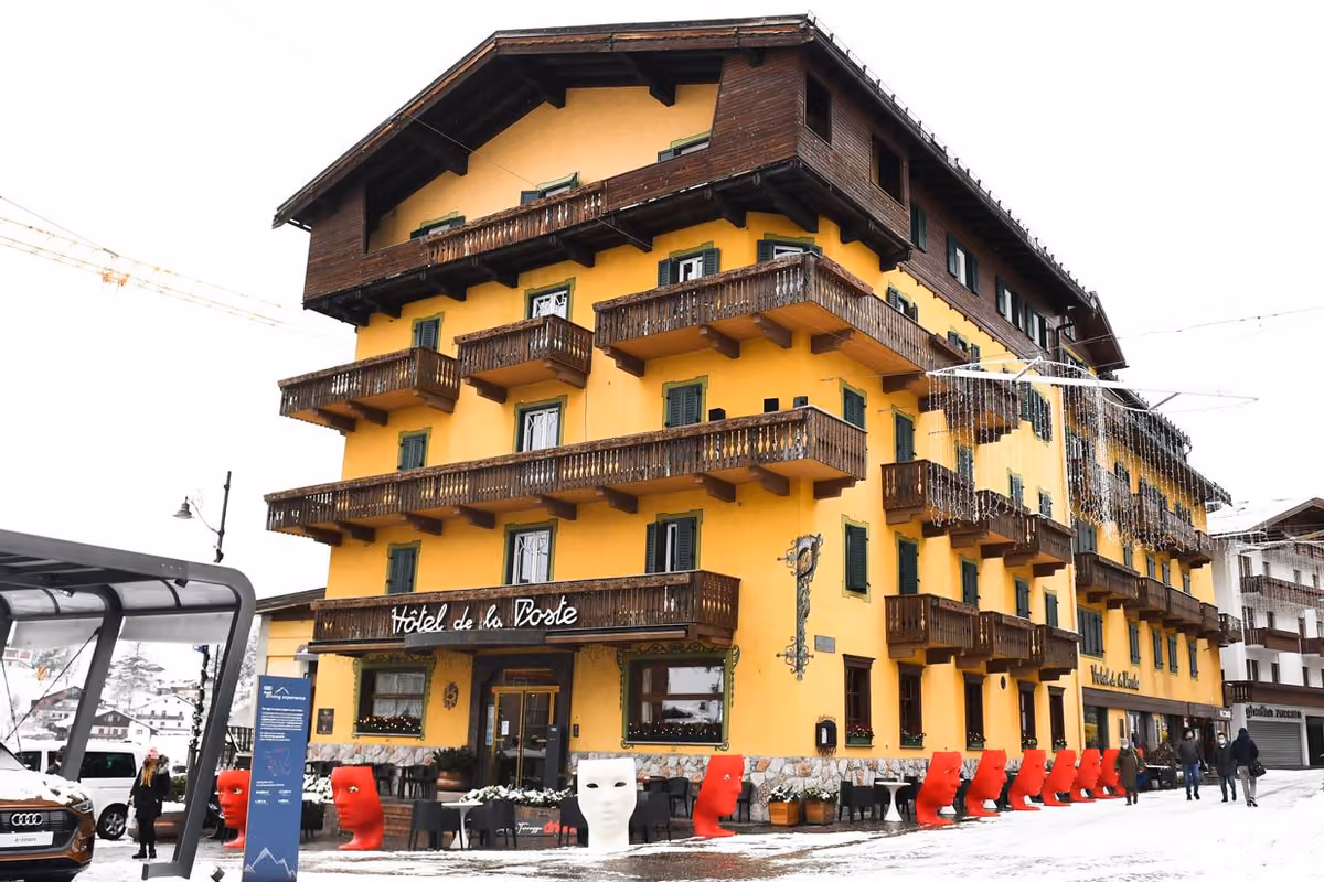 Hotel de la Poste con facciata gialla e balconi in legno a Cortina