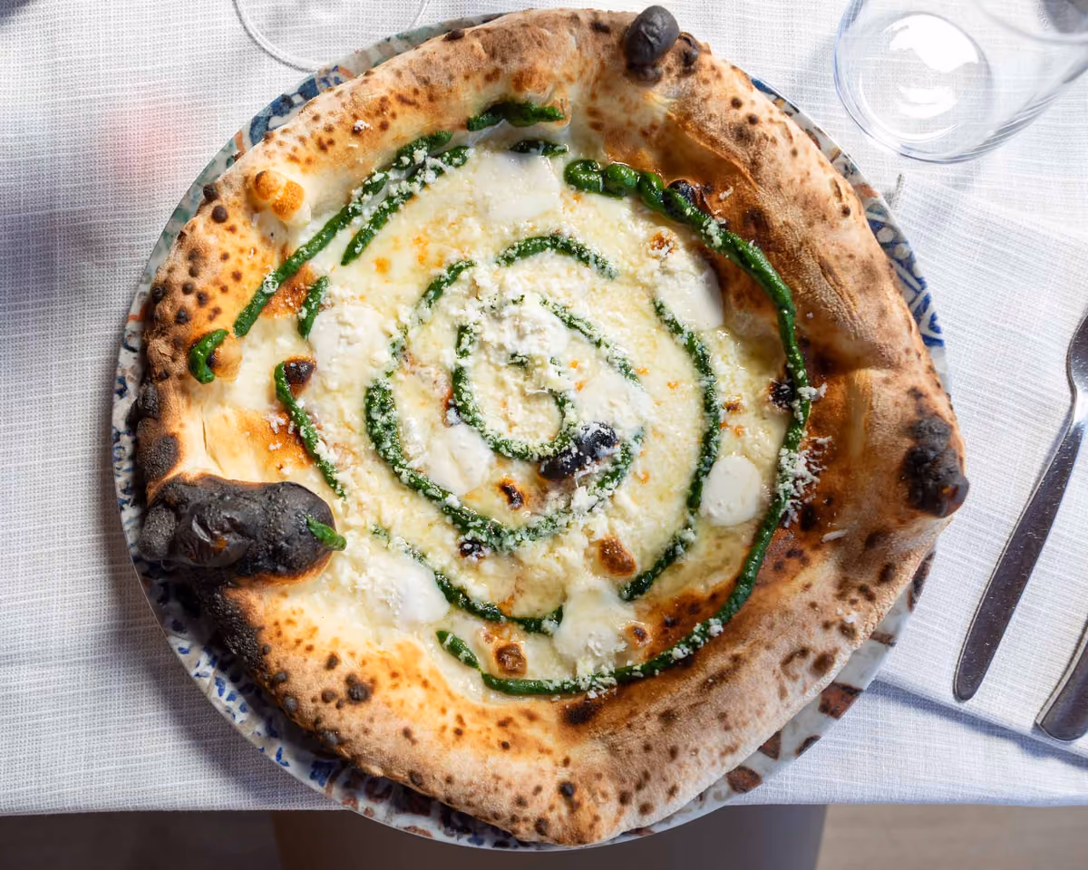 Pizza bianca con spirale di salsa verde su piatto decorato