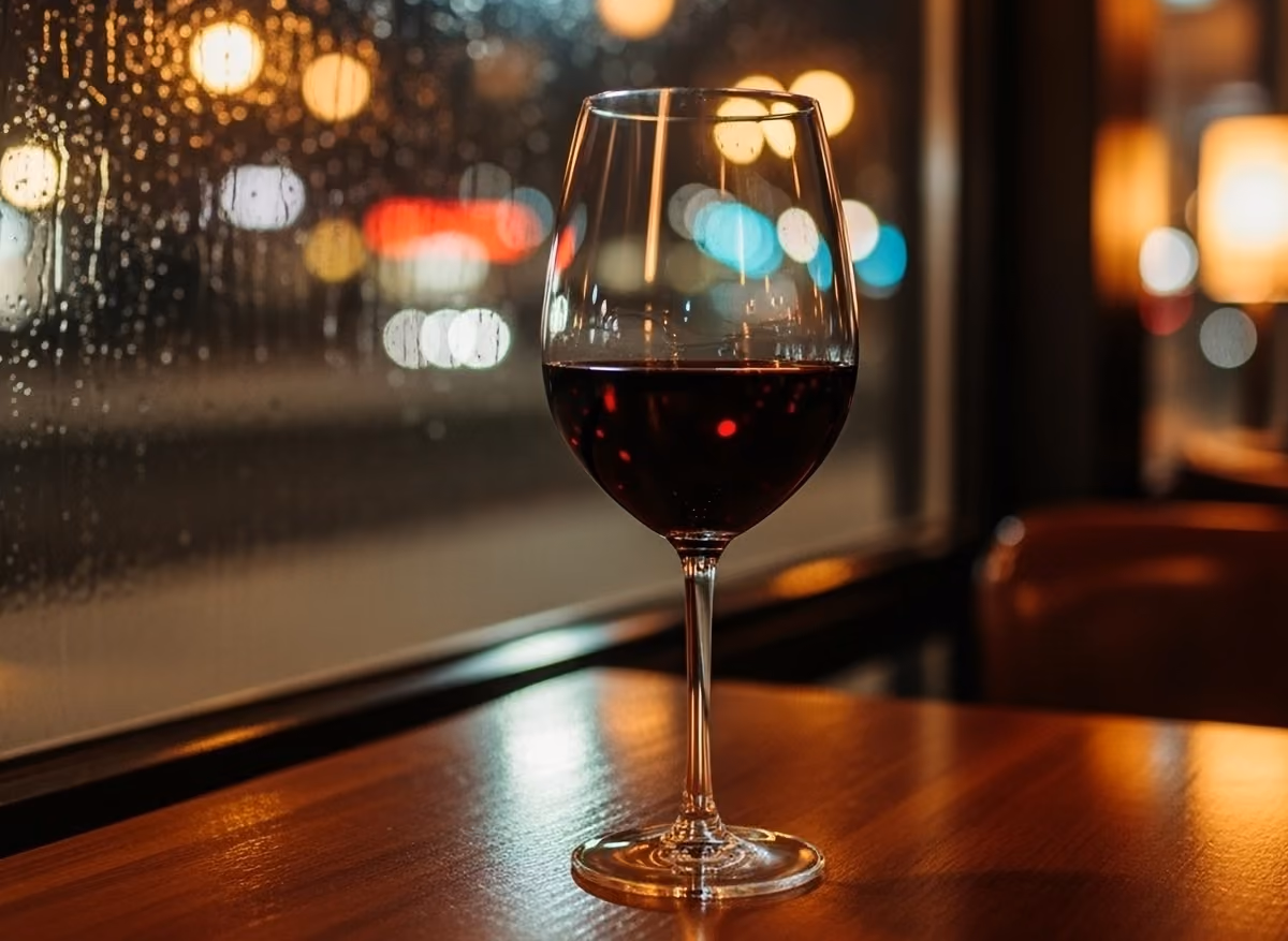 Un calice di vino rosso su un tavolo in un ristorante con luci notturne