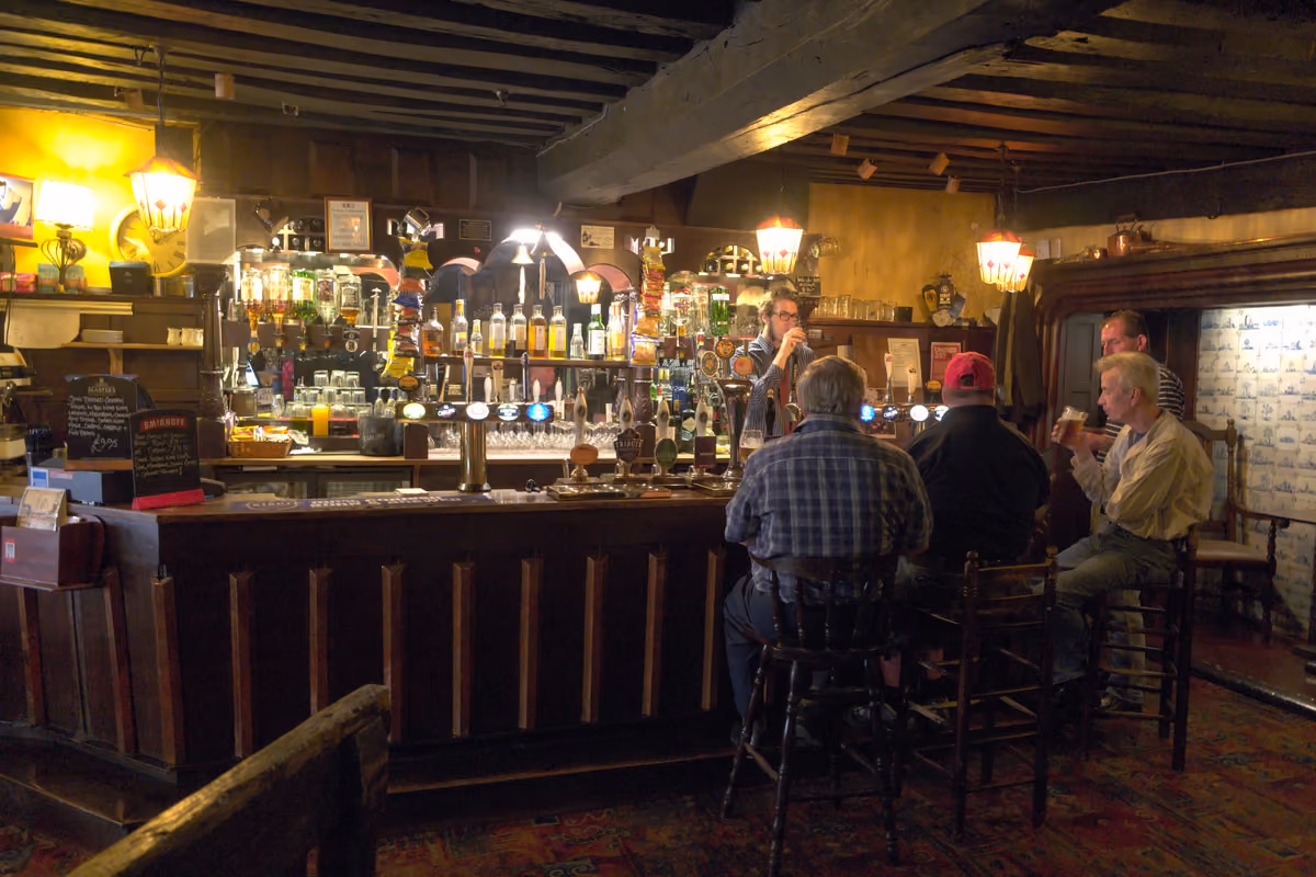 Small glass of beer with bar snacks on wooden pub table, casual dining