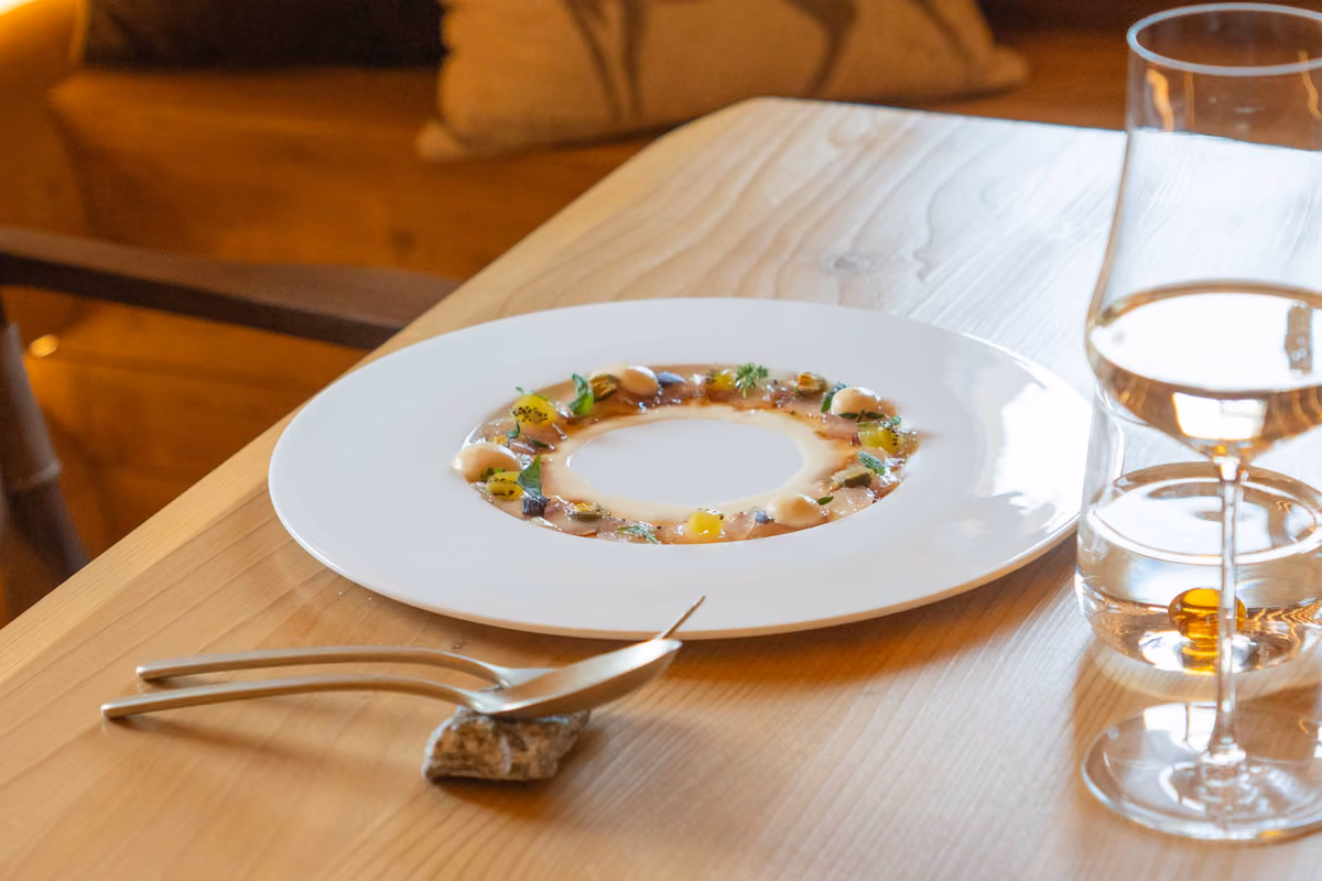 piatto gourmet disposto ad anello su tavola in legno con posate e bicchiere