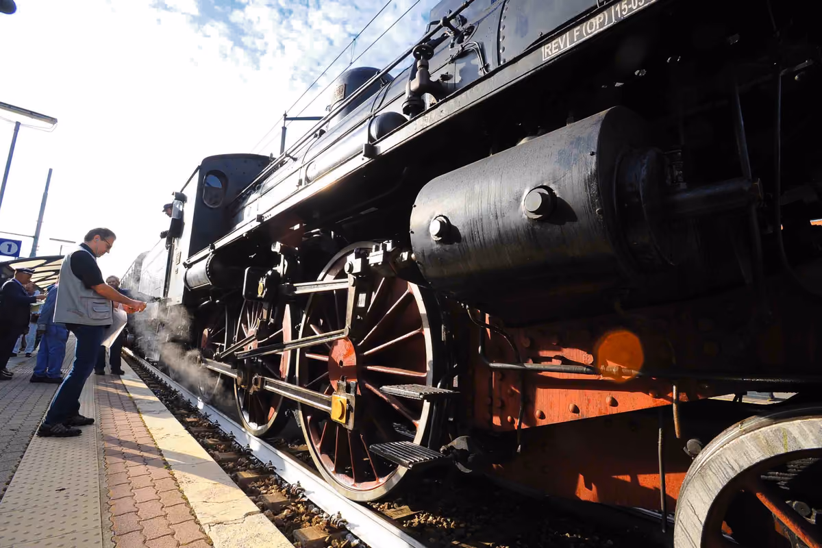 locomotiva a vapore ferma su un binario con uomo accanto alla banchina