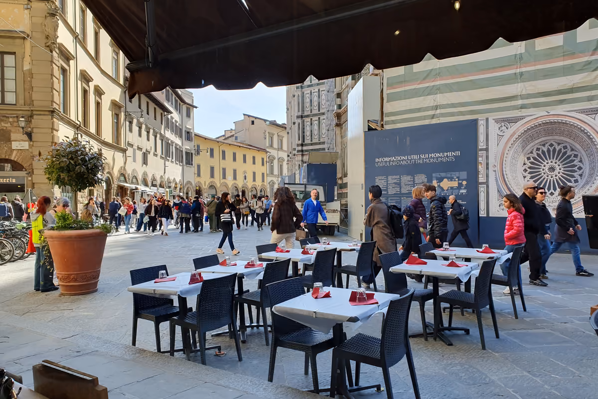 tavolini all'aperto di un ristorante in una piazza affollata del centro storico