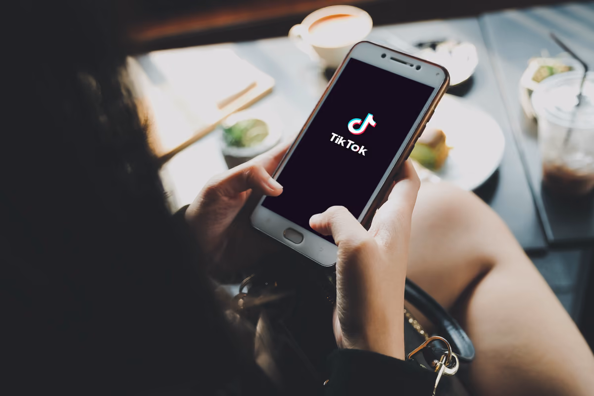 persona che tiene uno smartphone con il logo dell'applicazione TikTok sullo schermo