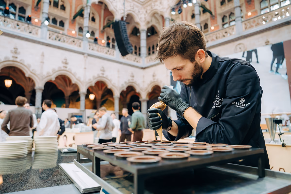 Chef con divisa nera riempie stampi di cioccolato in una sala elegante
