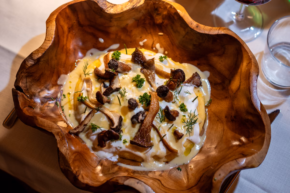 Piatto cremoso con funghi saltati ed erbe aromatiche servito in una ciotola rustica